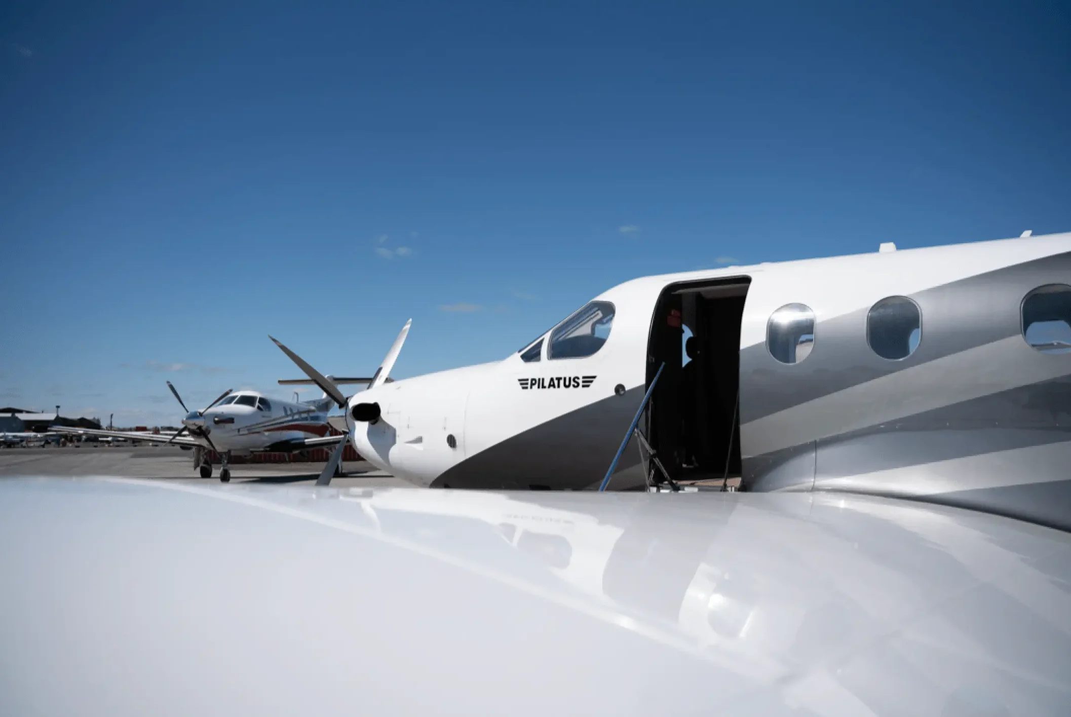 Avion Pilatus stationné sur le tarmac avec porte ouverte, sous un ciel dégagé